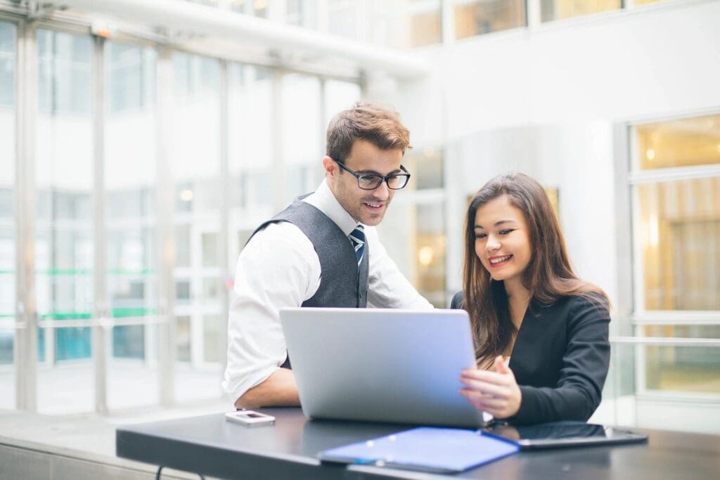 Two business people engaged in business development services, looking at a laptop in an office. Guidde the power of video documentation