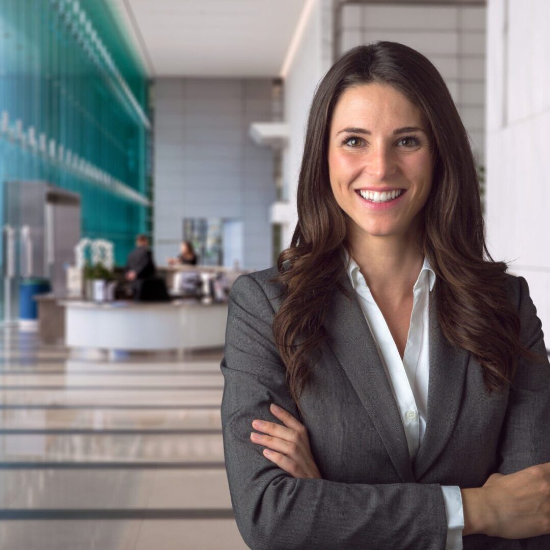 A smiling business woman in an office, ready to start your journey to transform your business.