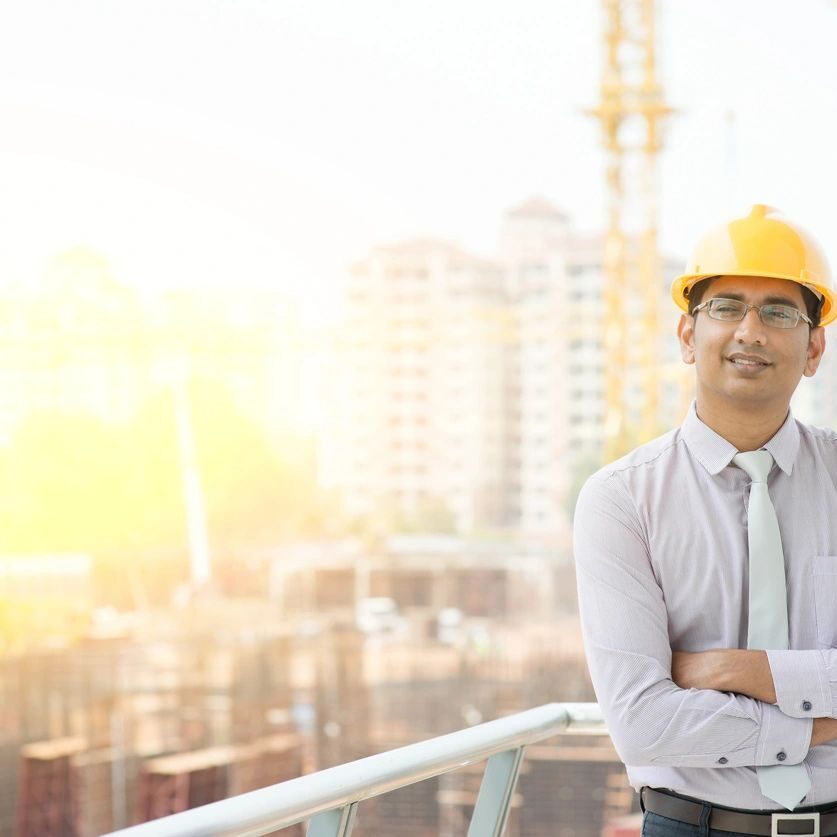 Contractor or business owner standing at a building construction site with arms folded and smiling