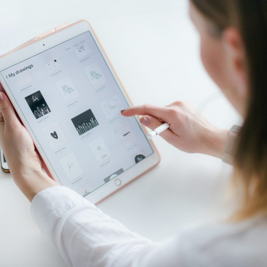 A woman is using an ipad on a white table.