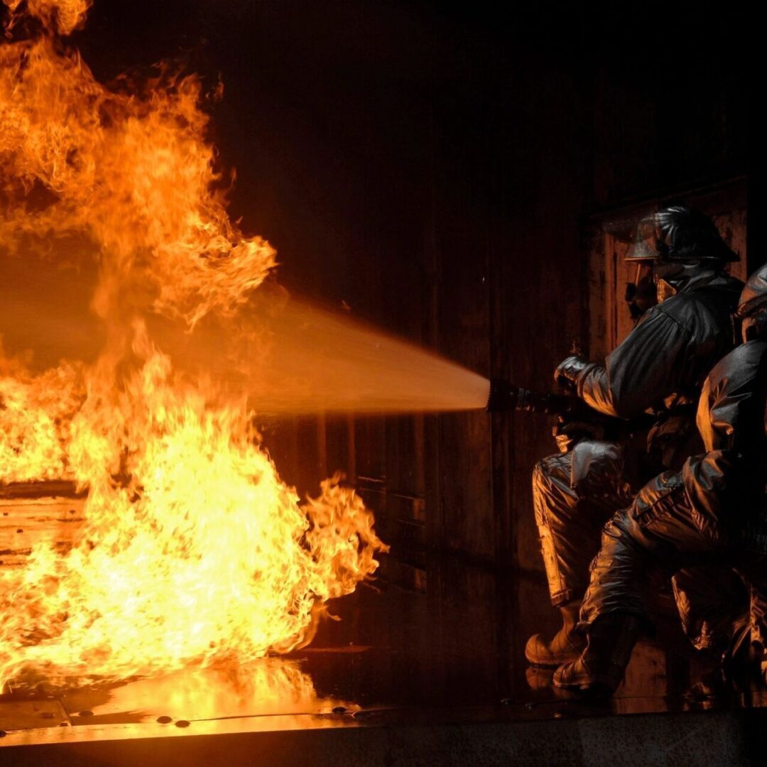 A firefighter is battling a fire with a hose.