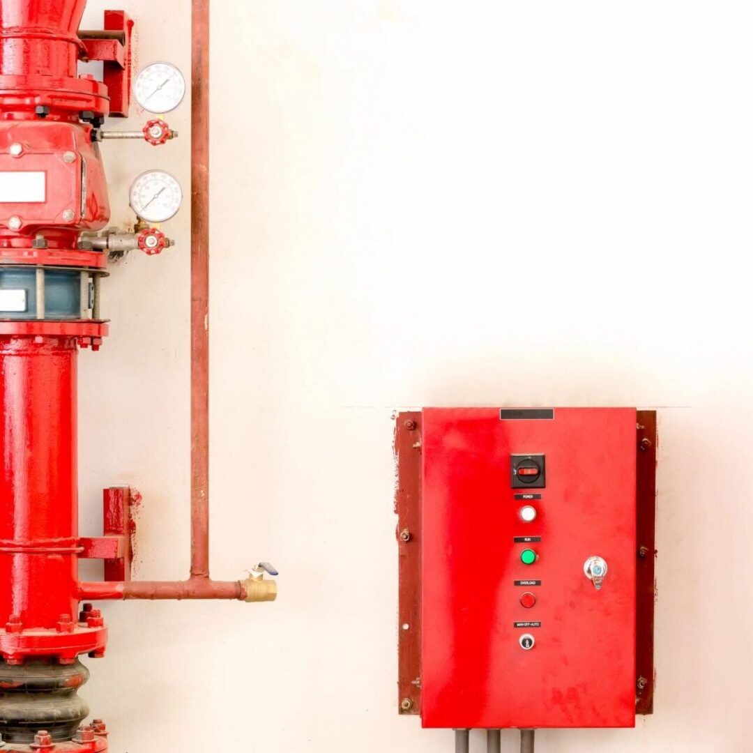 A red fire hydrant next to a white wall.