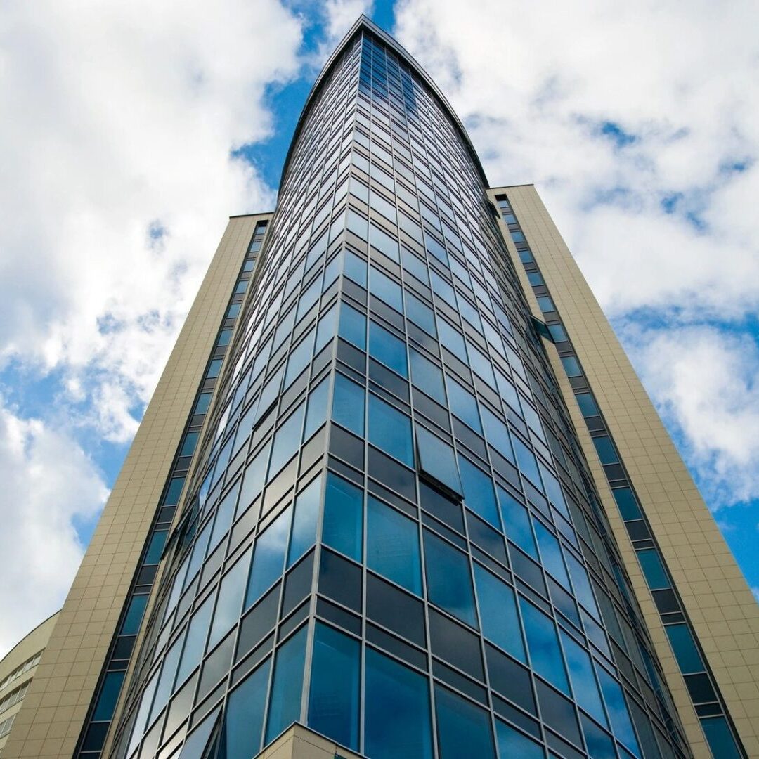 A tall glass building with a blue sky behind it.