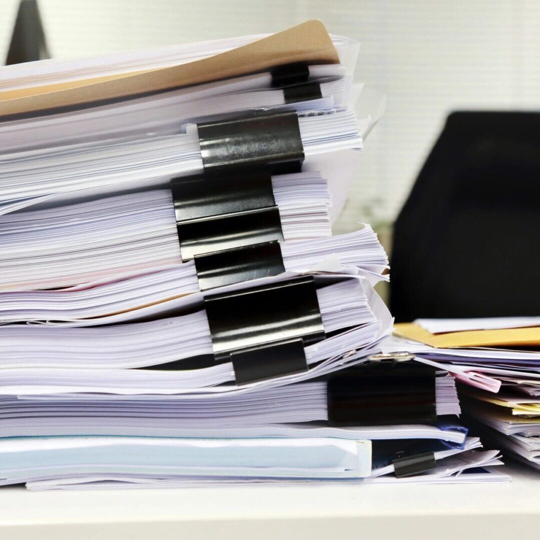 A pile of papers on a desk in an office.